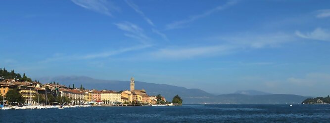 Trip Lettland beliebte Urlaubsziele am Gardasee -  Mit einer Fläche von 370 km² ist der Gardasee der größte See Italiens. Es liegt am Fuße der Alpen und erstreckt sich über drei Staaten: Lombardei, Venetien und Trentino. Die maximale Tiefe des Sees beträgt 346 m, er hat eine längliche Form und sein nördliches Ende ist sehr schmal. Dort ist der See von den Bergen der Gruppo di Baldo umgeben. Du trittst aus deinem gemütlichen Hotelzimmer und es begrüßt dich die warme italienische Sonne. Du blickst auf den atemberaubenden Gardasee, der in zahlreichen Blautönen schimmert - von tiefem Dunkelblau bis zu funkelndem Türkis. Majestätische Berge umgeben dich, während die Brise sanft deine Haut streichelt und der Duft von blühenden Zitronenbäumen deine Nase kitzelt. Du schlenderst die malerischen, engen Gassen entlang, vorbei an farbenfrohen, blumengeschmückten Häusern. Vereinzelt unterbricht das fröhliche Lachen der Einheimischen die friedvolle Stille. Du fühlst dich wie in einem Traum, der nicht enden will. Jeder Schritt führt dich zu neuen Entdeckungen und Abenteuern. Du probierst die köstliche italienische Küche mit ihren frischen Zutaten und verführerischen Aromen. Die Sonne geht langsam unter und taucht den Himmel in ein leuchtendes Orange-rot - ein spektakulärer Anblick.